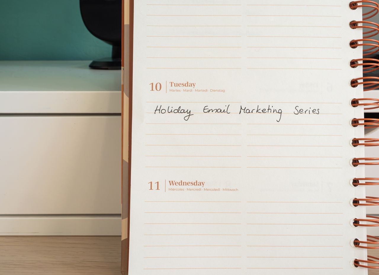 Planner ouvert sur un bureau avec une note manuscrite "Holiday Email Marketing Series".